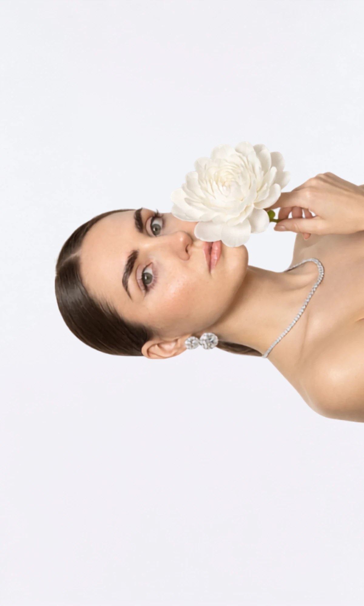 Model in a champagne dress holding a white flower